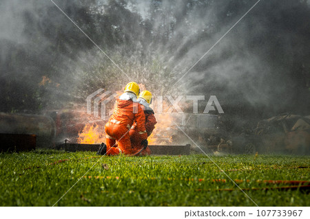 Firefighter Concept. Fireman using water and extinguisher to fighting with fire flame. 107733967