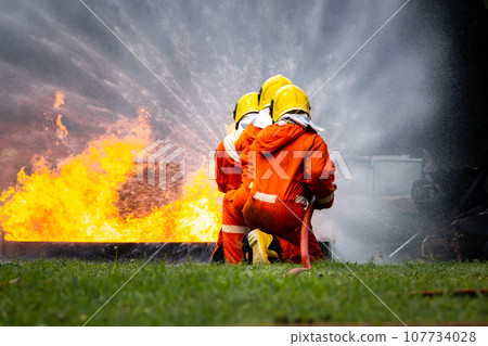 Firefighter Concept. Fireman using water and extinguisher to fighting with fire flame. Firefighter Concept. Fireman using water and extinguisher to fighting with fire flame. 107734028