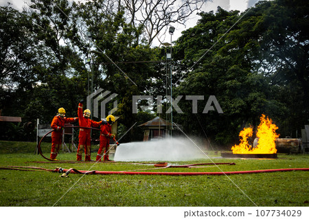 Firefighter Concept. Fireman using water and extinguisher to fighting with fire flame. Firefighter Concept. Fireman using water and extinguisher to fighting with fire flame. 107734029