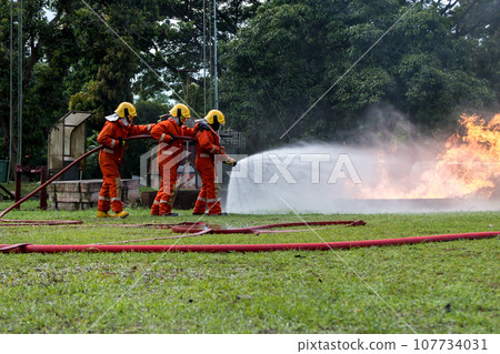 Firefighter Concept. Fireman using water and extinguisher to fighting with fire flame. Firefighter Concept. Fireman using water and extinguisher to fighting with fire flame. 107734031