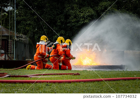 Firefighter Concept. Fireman using water and extinguisher to fighting with fire flame. 107734032