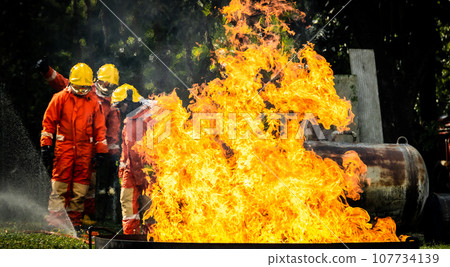 Firefighter Concept. Fireman using water and extinguisher to fighting with fire flame. Firefighter Concept. Fireman using water and extinguisher to fighting with fire flame. 107734139