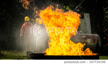 Firefighter Concept. Fireman using water and extinguisher to fighting with fire flame. Firefighter Concept. Fireman using water and extinguisher to fighting with fire flame. 107734140