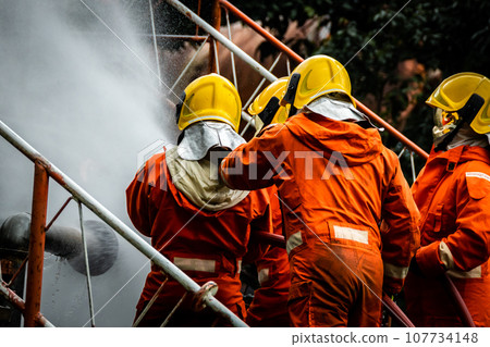 Firefighter Concept. Fireman using water and extinguisher to fighting with fire flame. 107734148