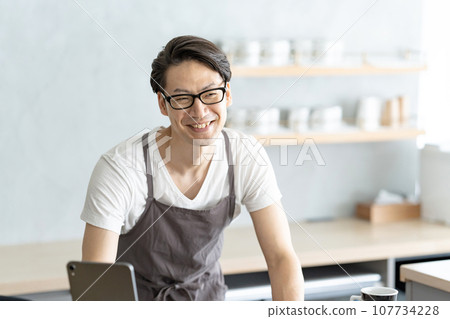 A male cafe clerk serving customers with a smile 107734228