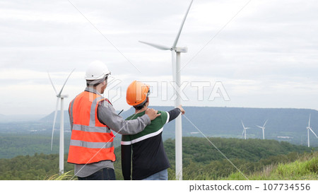Progressive engineer with his son in the wind farm atop of the mountain. 107734556