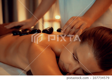 Hot stone massage at spa salon in luxury resort with warm candle light.Quiescent Hot stone massage at spa salon in luxury resort with warm candle light.Quiescent 107734579