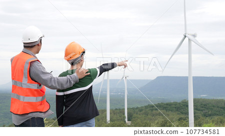 Progressive engineer with his son in the wind farm atop of the mountain. 107734581
