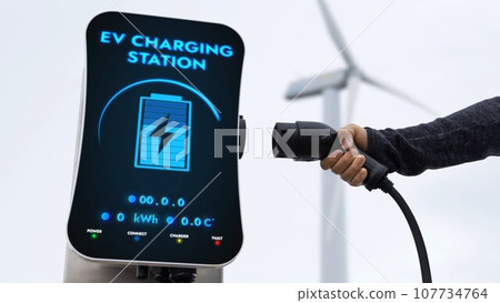 EV charger from EV car charging station at wind turbine. Persuse EV charger from EV car charging station at wind turbine. Persuse 107734764