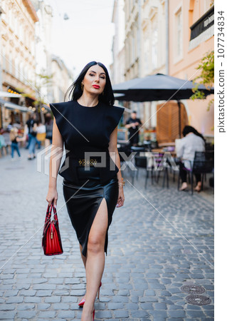Woman in fashionable black outfit walking gracefully in high heels on street Woman in fashionable black outfit walking gracefully in high heels on street 107734834
