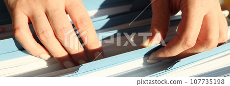 Secretary looks for folder with accounting papers in archive 107735198
