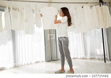 A woman hanging laundry to dry indoors A woman hanging laundry to dry indoors 107735488
