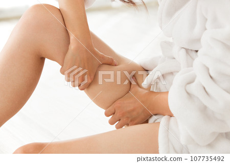 A woman is massaging her thighs. A woman is massaging her thighs. 107735492