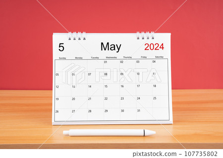 The May monthly desk calendar for 2024 year and pen on the wooden table with red color background. The May monthly desk calendar for 2024 year and pen on the wooden table with red color background. 107735802