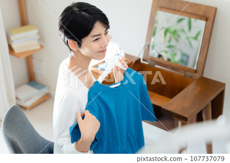 一個女人在她的房間裡挑選衣服 107737079