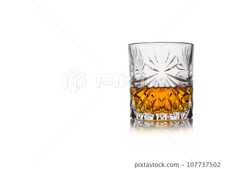 Scotch whiskey in crystal elegant glass on white background with reflection. 107737502