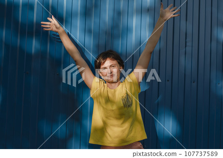 Joyful young brunette woman girl in light casual clothes posing on blue wall background. People emotions lifestyle concept. Mock up copy space. Spreading rising hands 107737589