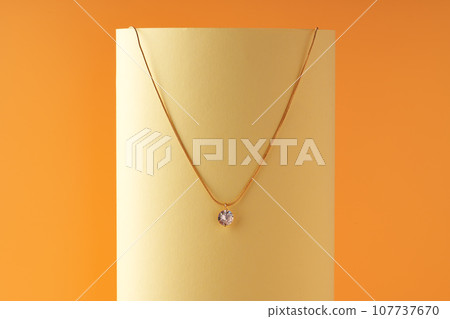 Golden chain with a pendant on yellow sheet of paper 107737670