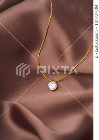 Golden necklace with pendant on silk background 107737684