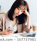 A woman who is tired from operating a computer and smartphone at the same time. electronic device neurosis 107737981