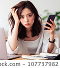 A woman who is tired from operating a computer and smartphone at the same time. electronic device neurosis 107737982
