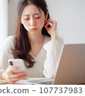 A woman who is tired from operating a computer and smartphone at the same time. electronic device neurosis 107737983