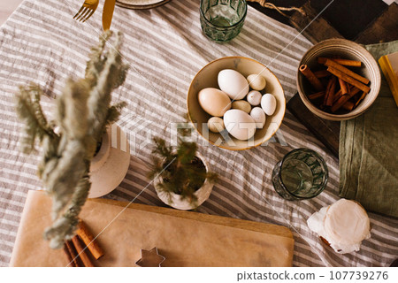 Molds for ginger cookies, rolling pin, eggs, cinnamon sticks on the table in a cozy kitchen Molds for ginger cookies, rolling pin, eggs, cinnamon sticks on the table in a cozy kitchen 107739276