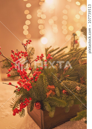 Floral arrangement in a wooden box with live spruce and ilex branches for decorating the house for the Christmas holidays.Christmas wooden box with fir branches for the holiday. The new year Floral arrangement in a wooden box with live spruce and ilex branches for decorating the house for the Christmas holidays.Christmas wooden box with fir branches for the holiday. The new year 107739513