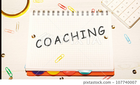 COACHING word on a checkered notebook on a light table next to a magnifying glass, paper clips, stationery buttons, a calculator COACHING word on a checkered notebook on a light table next to a magnifying glass, paper clips, stationery buttons, a calculator 107740007