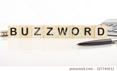 Buzzword - word word assembled from wooden cubes next to a calculator, pen and notepad 107740012