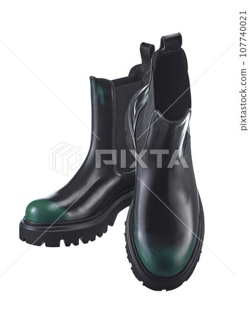 Beautiful pair of high demi-season boots made of black leather with a green spout, with a massive sole, isolated on a white background. 107740021