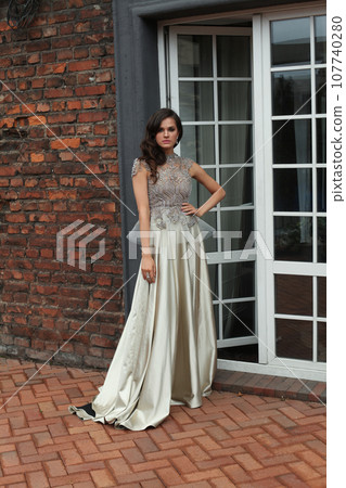 Perfect young woman in silver evening gown standing on the terrace 107740280