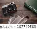 Vintage film camera, film and photo album on a dark wooden table. Top view 107740583
