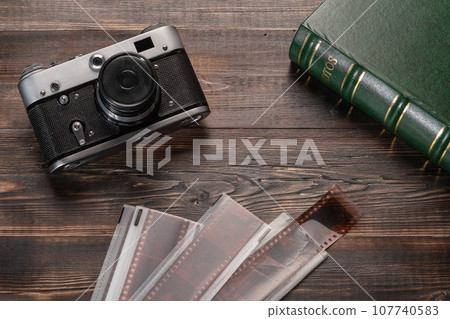 Vintage film camera, film and photo album on a dark wooden table. Top view 107740583