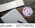Laptop with headphones, CD and music paper with pen on wooden background. Copy space for your text 107740592