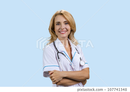 Happy smiling female doctor with folded arms. Isolated on blue. Happy smiling female doctor with folded arms. Isolated on blue. 107741348