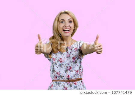 Happy young caucasian female gives both thumbs up. Isolated on pink. Happy young caucasian female gives both thumbs up. Isolated on pink. 107741479