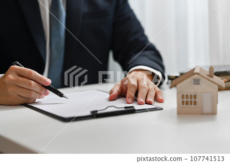 Male realtor writing document, preparing contract for the customer. Real estate, loan and property investment concept Male realtor writing document, preparing contract for the customer. Real estate, loan and property investment concept 107741513