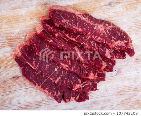 Uncooked beef fillet with parsley and garlic on table 107742109
