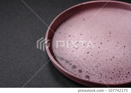 Empty round ceramic plate on a dark textured background 107742175
