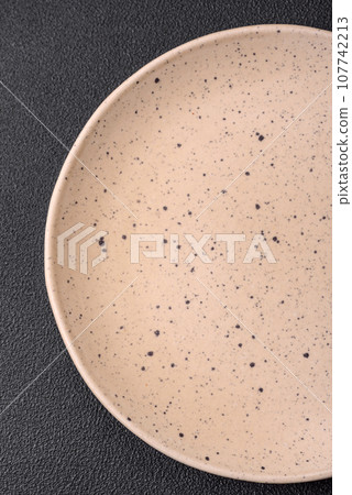 Empty round ceramic plate on a dark textured background 107742213