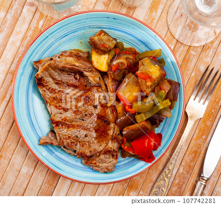 Beef steak with baked eggplants, bell peppers, onion and tomatoes 107742281