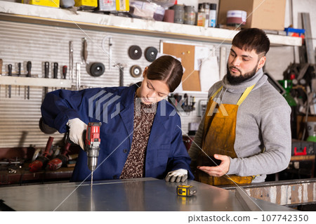 Woman working with metal sheet and using electric drill Woman working with metal sheet and using electric drill 107742350