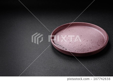 Empty ceramic plate on a dark textured background Empty ceramic plate on a dark textured background 107742638