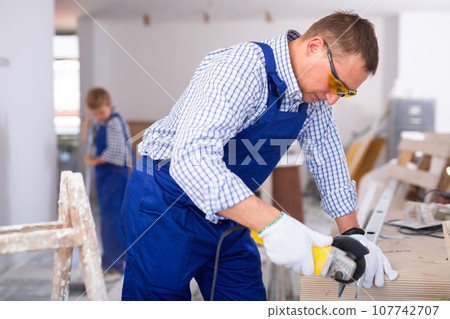 Focused man renovating home, cutting metal profile Focused man renovating home, cutting metal profile 107742707