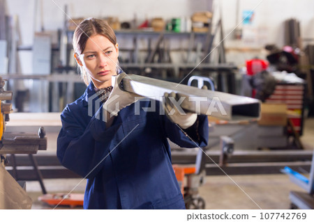 Workwoman inspecting steel stocks in workshop 107742769