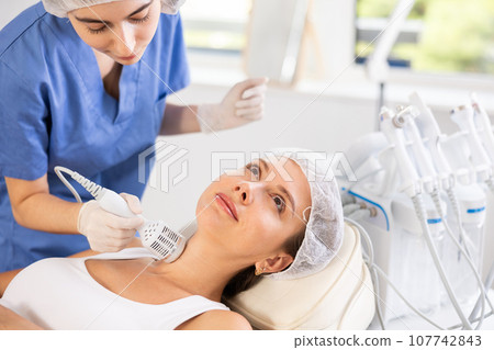 Young female cosmetologist performing neck whitening procedure on young woman Young female cosmetologist performing neck whitening procedure on young woman 107742843