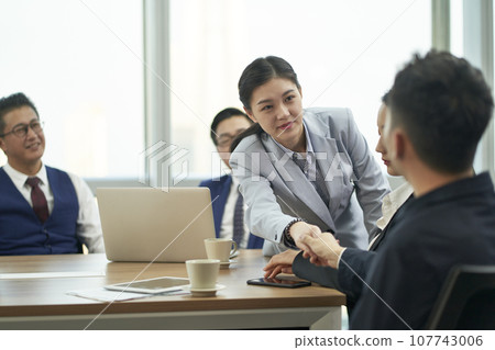 young asian businessman and businesswoman shaking hands during meeting young asian businessman and businesswoman shaking hands during meeting 107743006