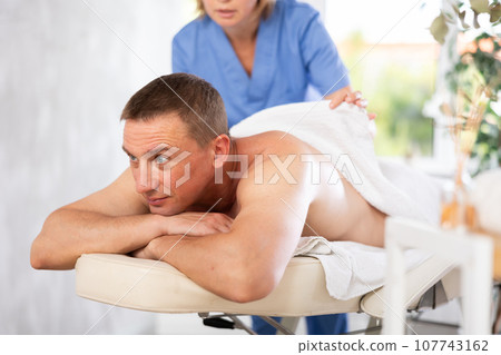 the woman ensures the man is comfortably covered with a towel 107743162