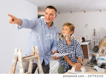 Little son with father together checking blueprints before renovating room 107743242